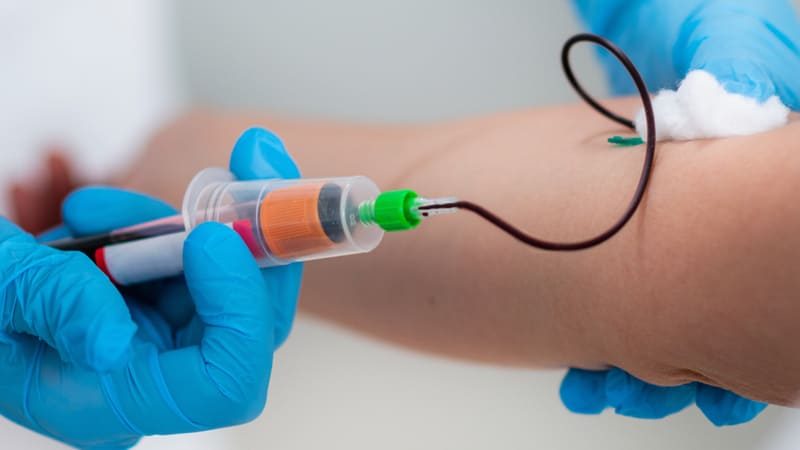 Profissional de saúde coleta sangue para exame de glicemia.