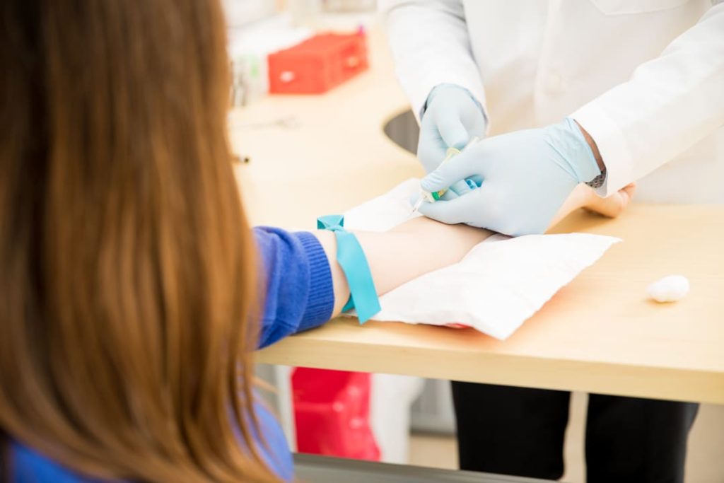 Profissional de saúde coletando sangue do braço de uma paciente para exames de rotina.
