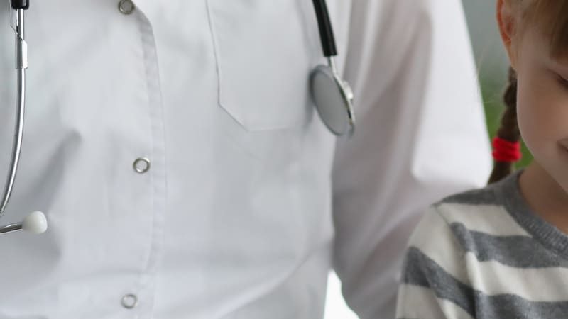 Médico com jaleco branco e estetoscópio ao lado de uma criança sorridente, representando atendimento pediátrico relacionado a doenças comuns na infância.