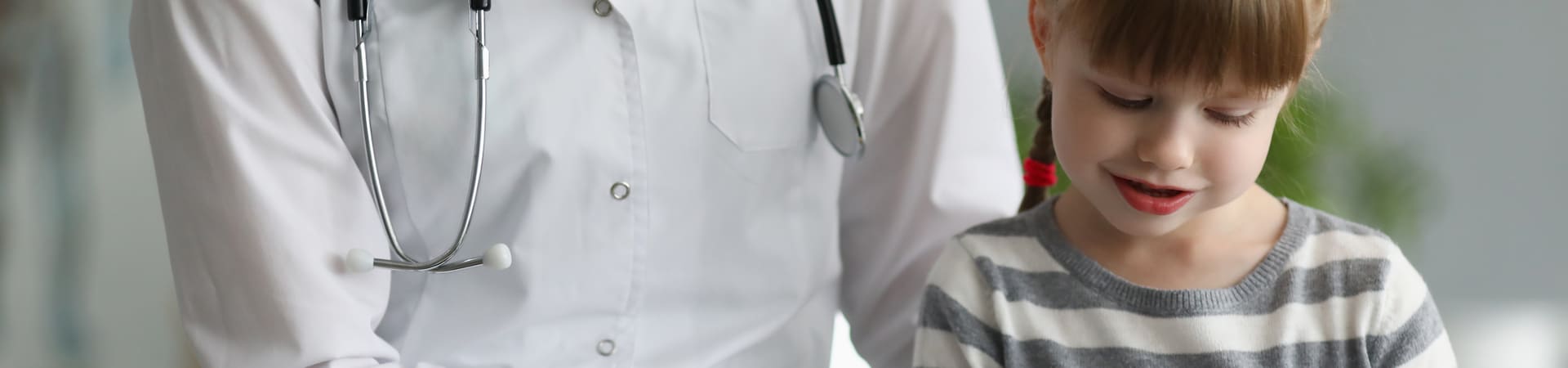 Médico com jaleco branco e estetoscópio ao lado de uma criança sorridente, representando atendimento pediátrico relacionado a doenças comuns na infância.