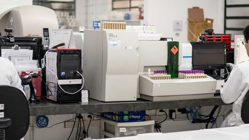 Profissionais de laboratório trabalhando em análises clínicas com equipamentos modernos.