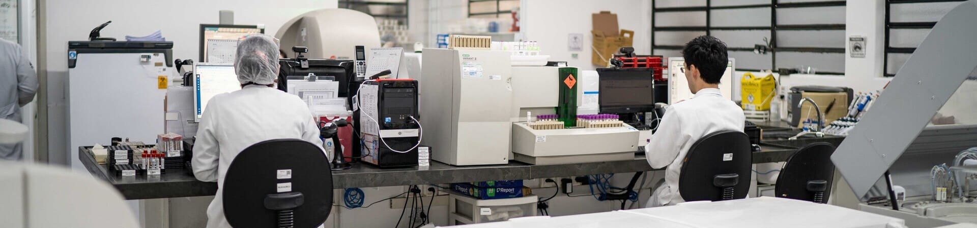 Profissionais de laboratório trabalhando em análises clínicas com equipamentos modernos.
