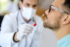 Profissional de saúde coleta amostra nasal com swab para realização do exame de painel viral respiratório em um paciente.