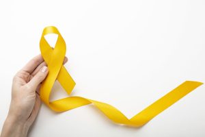Mão segurando um laço amarelo, símbolo da campanha Setembro Amarelo de conscientização sobre a prevenção ao suicídio.