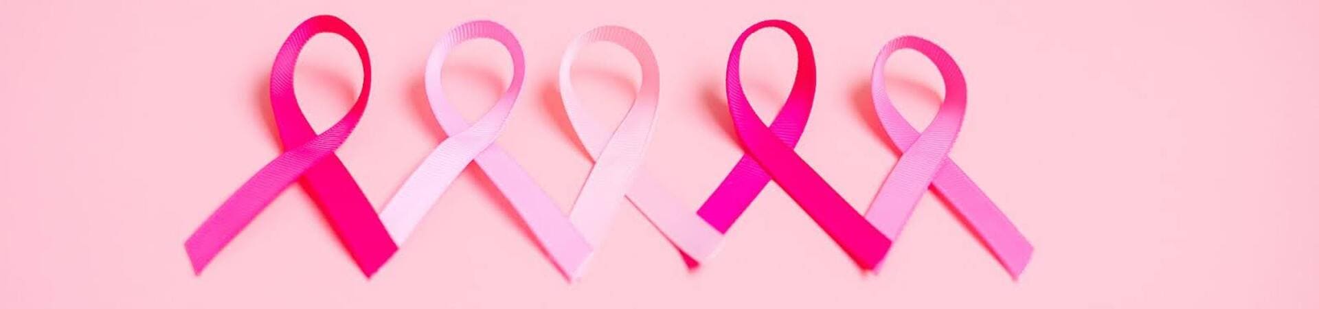 Laços cor-de-rosa alinhados sobre fundo rosa, símbolo do Outubro Rosa, campanha mundial de conscientização sobre a prevenção e o diagnóstico precoce do câncer de mama.
