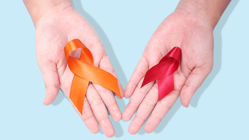 Mãos abertas segurando dois laços de conscientização, um vermelho e um laranja, símbolos das campanhas de prevenção ao HIV e ao câncer de pele.