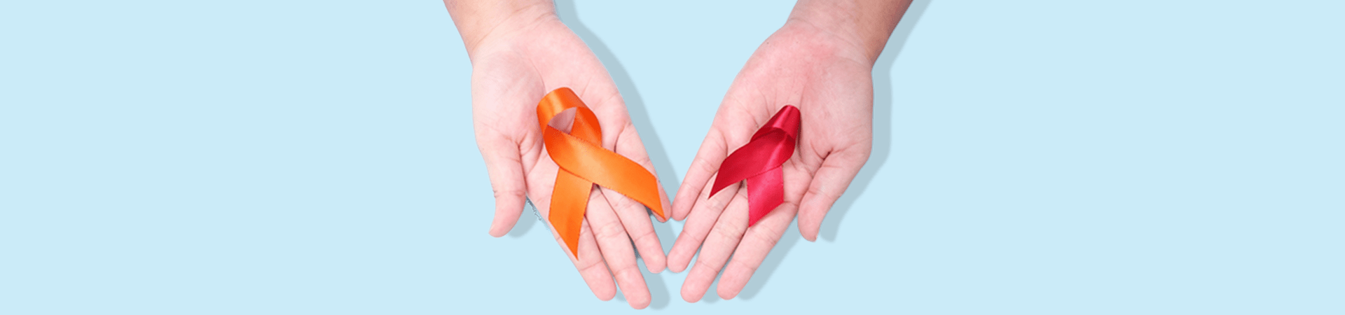 Mãos abertas segurando dois laços de conscientização, um vermelho e um laranja, símbolos das campanhas de prevenção ao HIV e ao câncer de pele.
