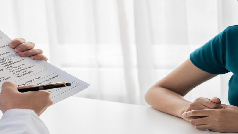 Profissional de saúde analisando ficha médica durante atendimento, representando a importância do check-up anual para acompanhamento da saúde.