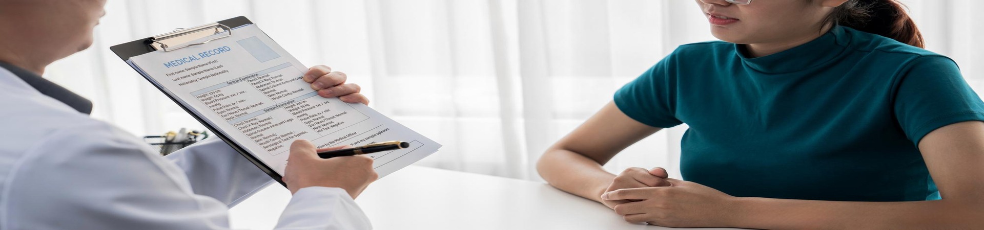 Profissional de saúde analisando ficha médica durante atendimento, representando a importância do check-up anual para acompanhamento da saúde.