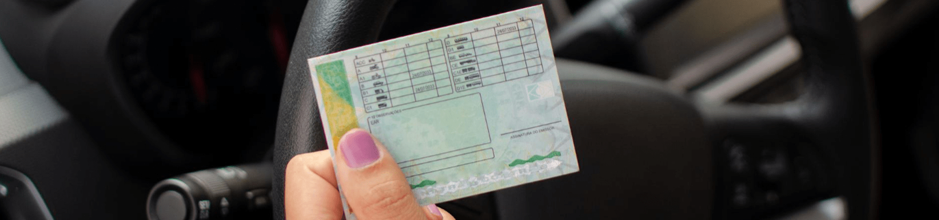 Pessoa segurando documento da CNH dentro de um carro, representando a obrigatoriedade do exame toxicológico CNH para motoristas.