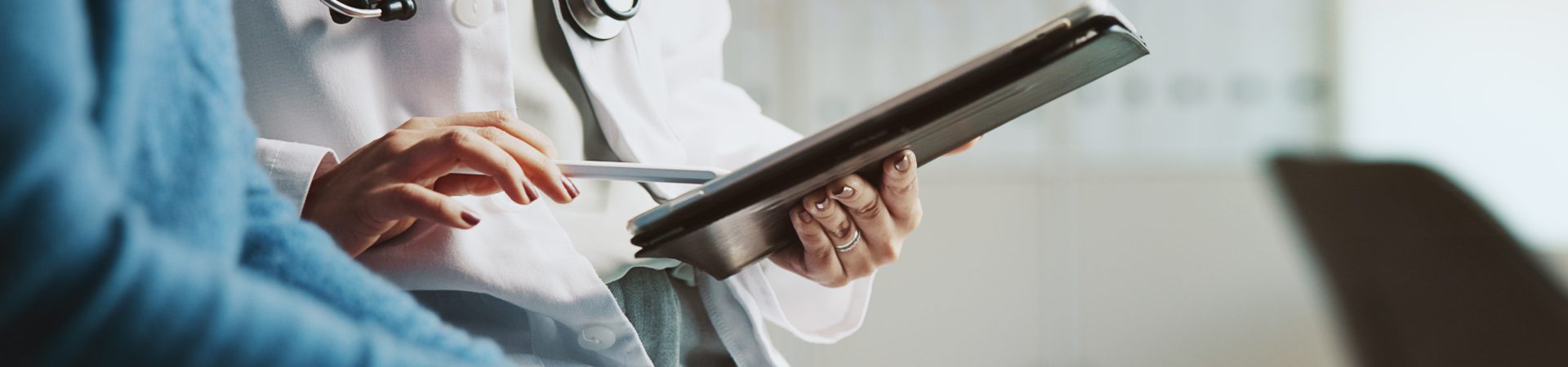 Profissional de saúde utilizando tablet durante consulta, organizando exames laboratoriais com agendamento para facilitar o acompanhamento da saúde.