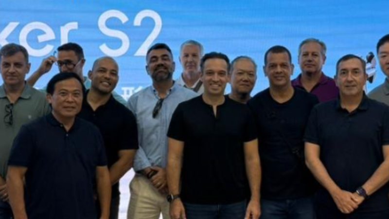 Grupo de profissionais reunidos em evento corporativo internacional diante de painel tecnológico Walker S2.