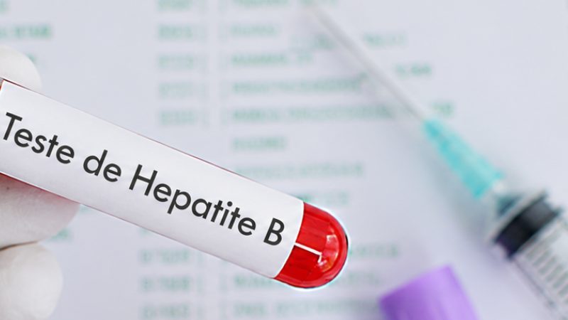 Tubo de coleta de sangue identificado para teste de Hepatite B ao lado de uma seringa.