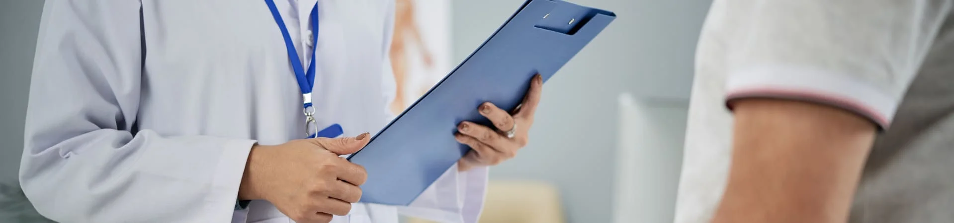Médica segurando prancheta durante consulta com paciente para discutir os resultados de seus exames de função hepática.